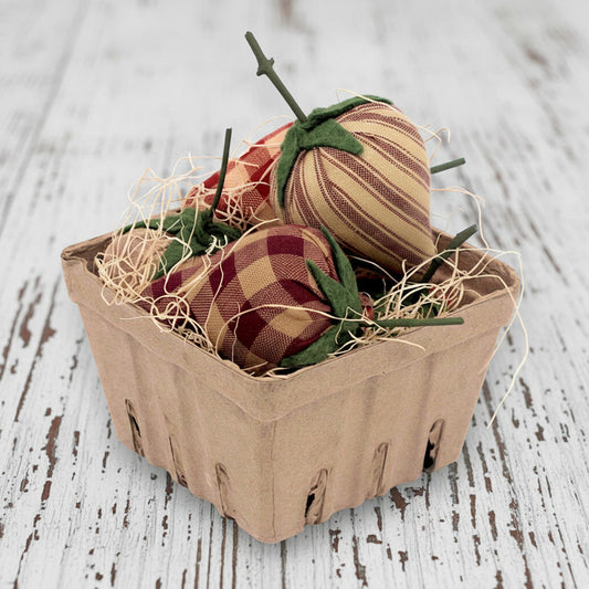 Decorative fabric strawberries in a cardboard basket on a wooden surface