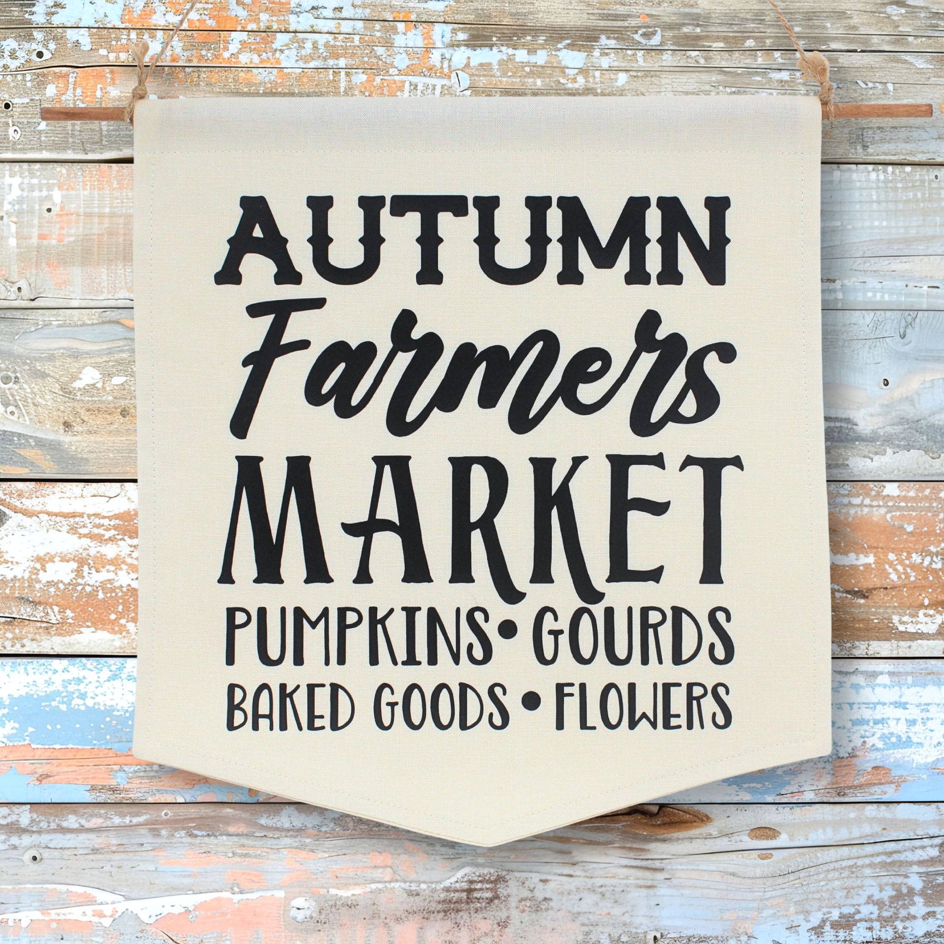 Cotton fabric sign with 'Autumn Farmers Market' text on a wooden background