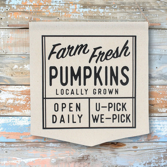 Canvas sign with 'Farm Fresh Pumpkins' text on a wooden background