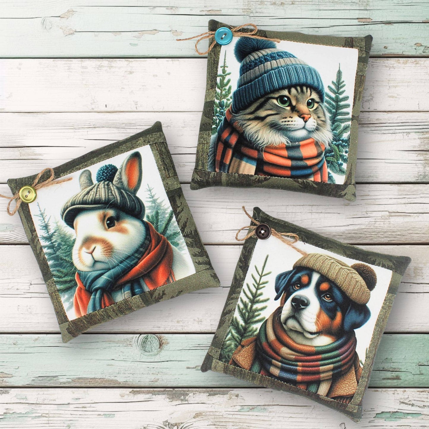 Three decorative pillows with animal illustrations wearing hats and scarves on a wooden surface.