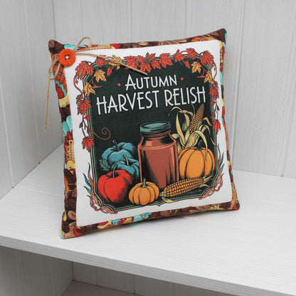 Decorative pillow with autumn harvest design featuring pumpkins, corn, and a jar.