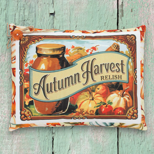 Decorative pillow with 'Autumn Harvest Relish' design on a wooden surface