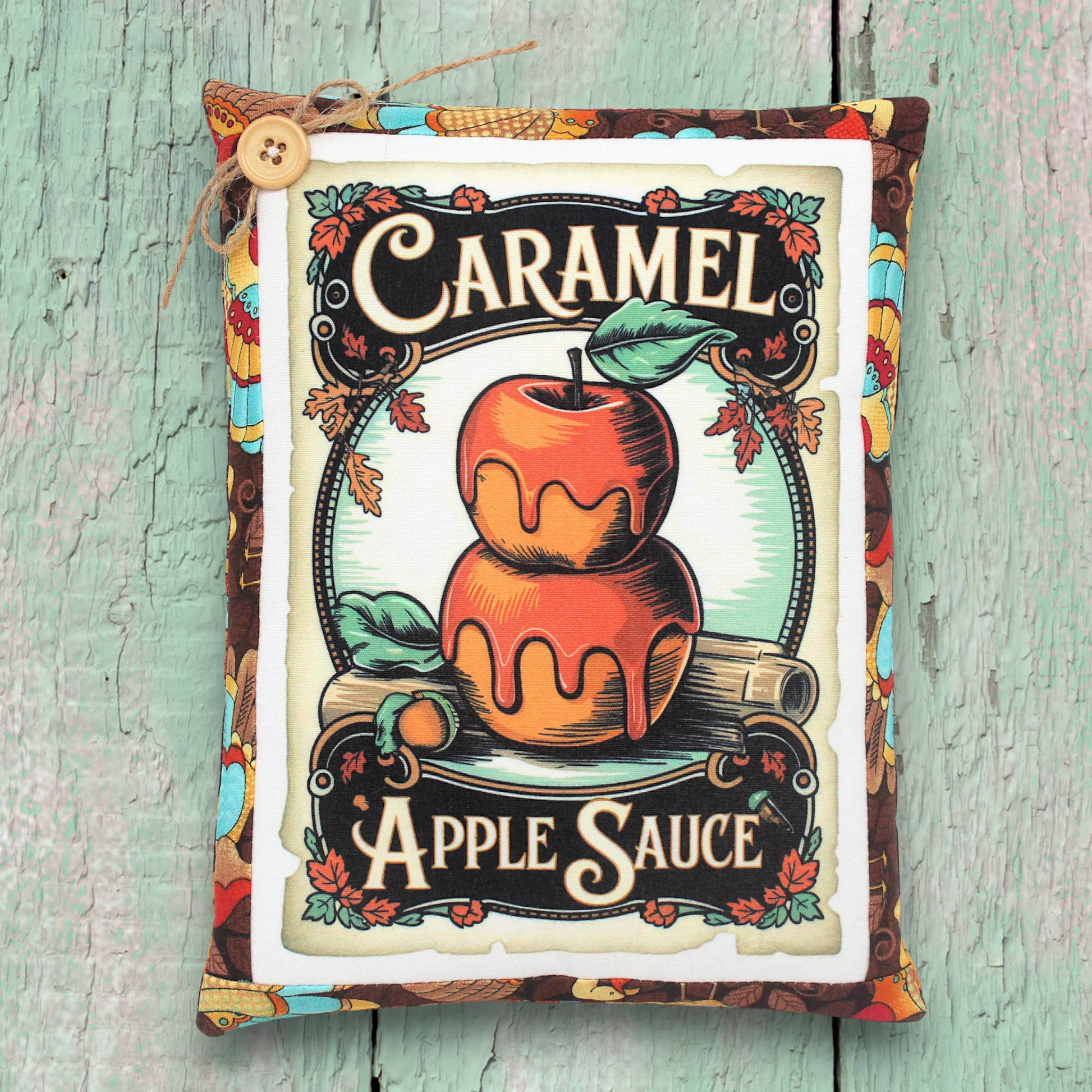 Vintage-style label for caramel apple sauce with an apple illustration on a wooden surface.