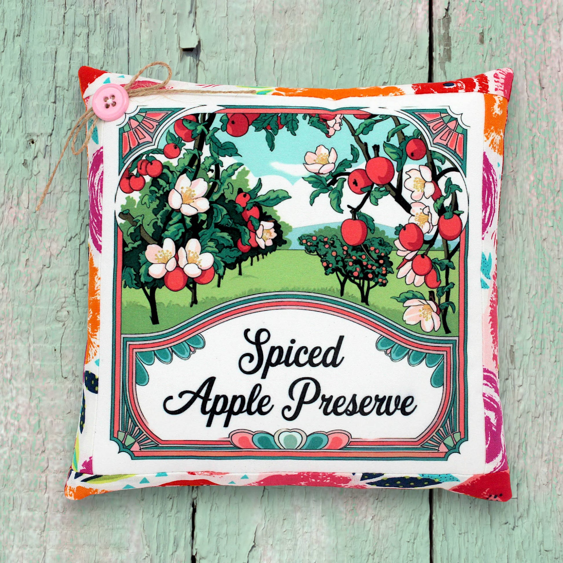 Decorative small pillow for 'Spiced Apple Preserve' with apple tree illustration on a wooden surface.