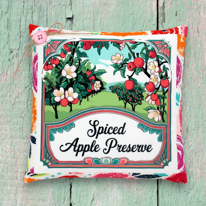 Decorative small pillow for 'Spiced Apple Preserve' with apple tree illustration on a wooden surface.