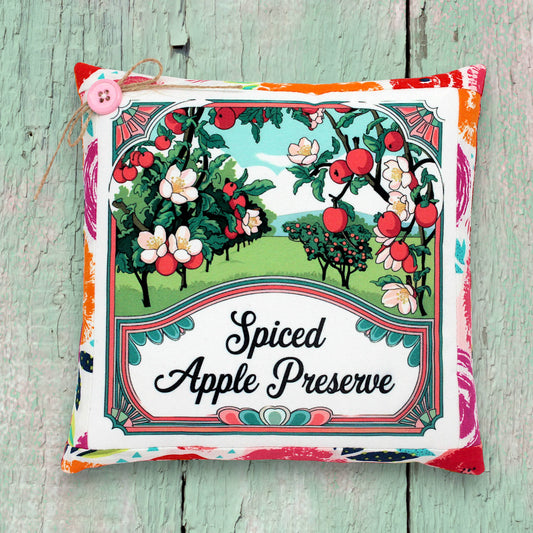 Decorative small pillow for 'Spiced Apple Preserve' with apple tree illustration on a wooden surface.