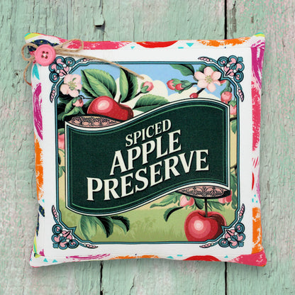 Decorative pillow with 'Spiced Apple Preserve' design on a wooden surface