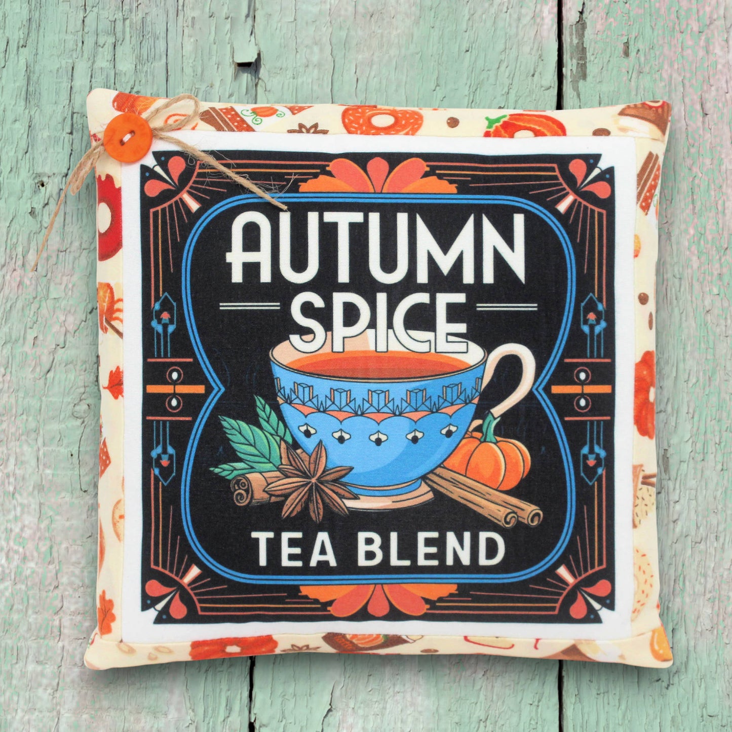 Decorative pillow with 'Autumn Spice Tea Blend' design on a wooden surface