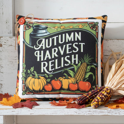Decorative pillow with 'Autumn Harvest Relish' design featuring pumpkins, corn, and apples on a white background.
