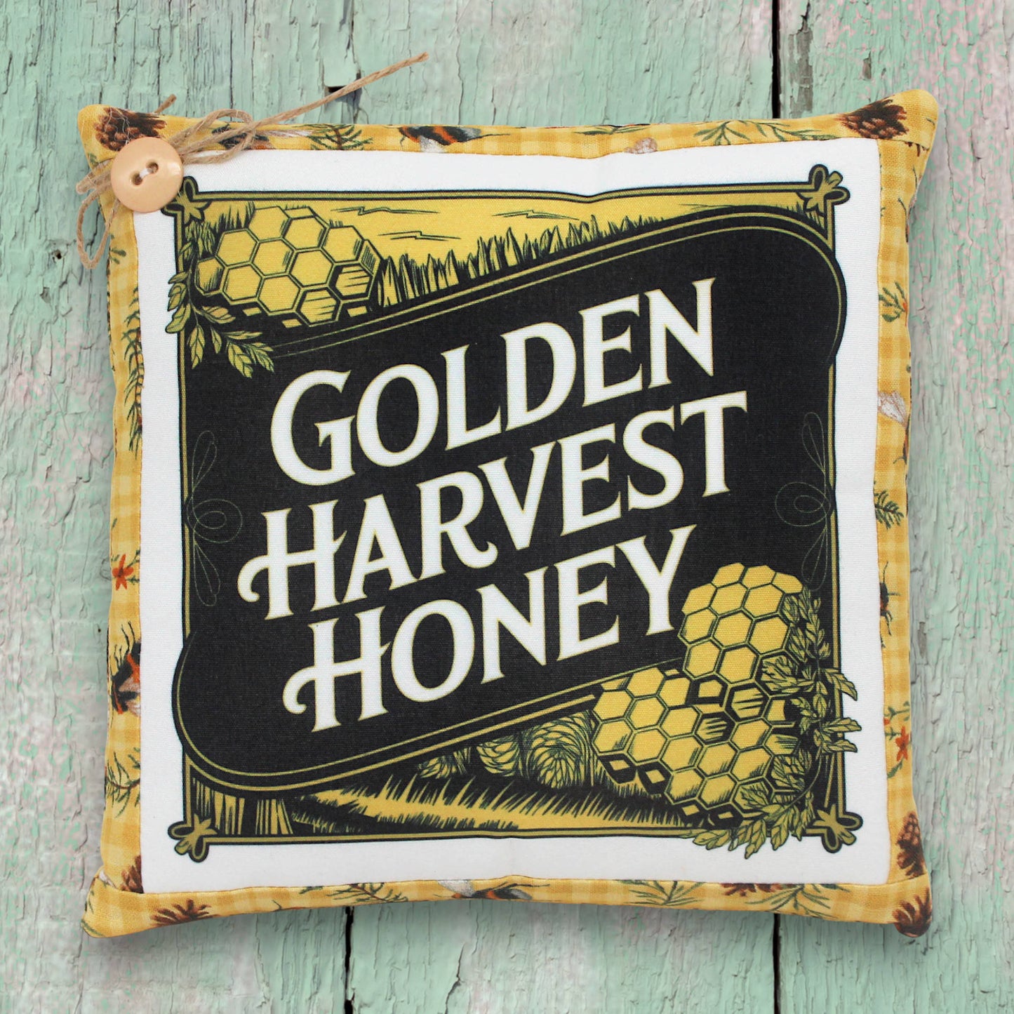 Decorative small pillow with 'Golden Harvest Honey' text on a wooden surface