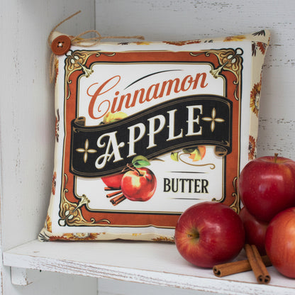 Decorative pillow with 'Cinnamon Apple Butter' design on a white background