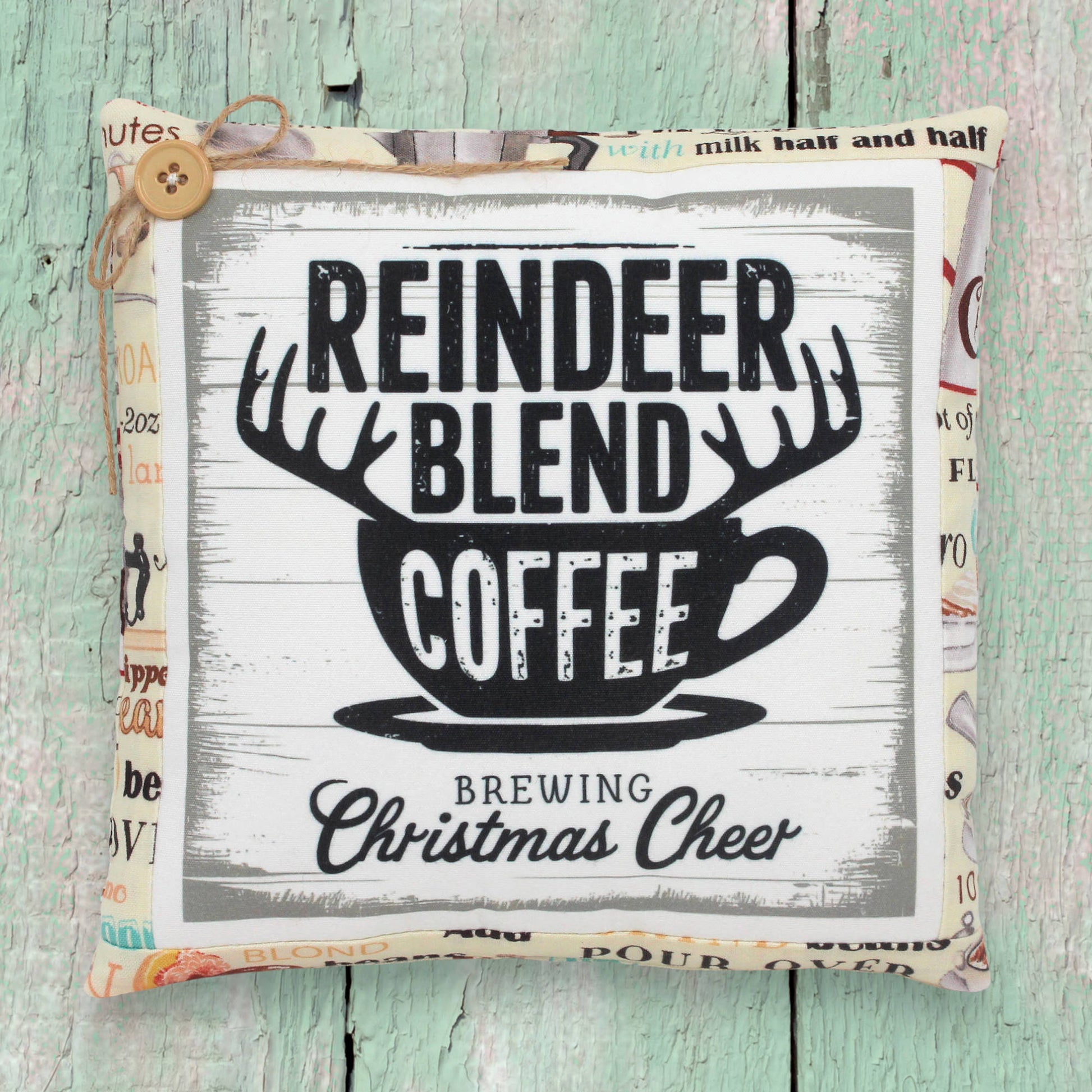Decorative pillow with 'Reindeer Blend Coffee' text on a wooden surface