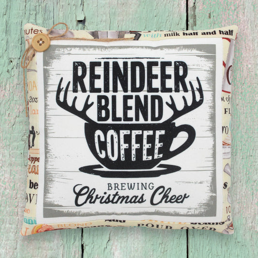 Decorative pillow with 'Reindeer Blend Coffee' text on a wooden surface