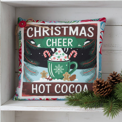 Decorative pillow with Christmas cheer and hot cocoa design on a white background