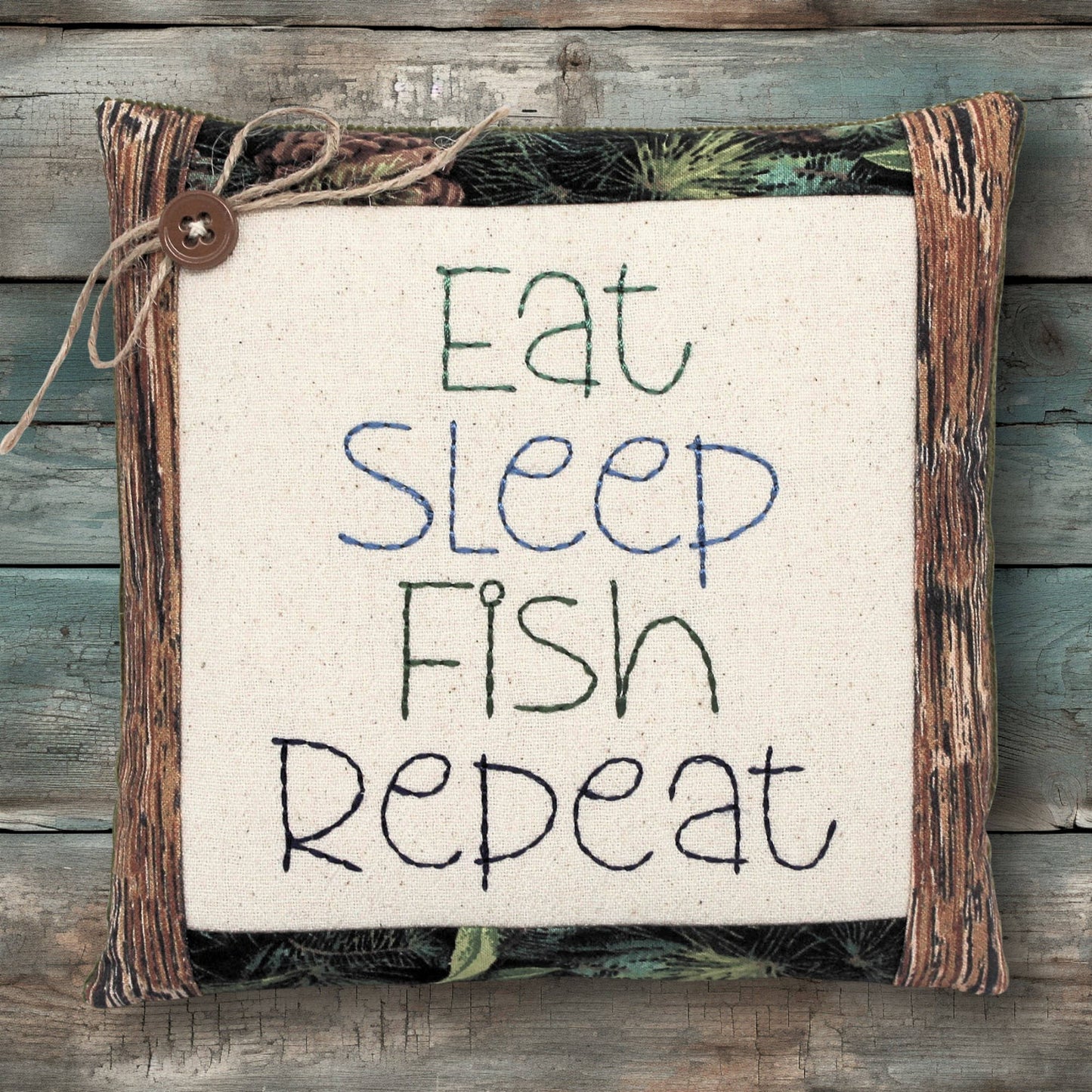 Miniature pillow embroidered with the words 'eat sleep fish repeat'